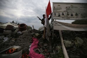 Armed pro-Russian militiaman from Vostok Batallion removes flags of other separatist groups on the barricades outside the Donetsk regional administration building